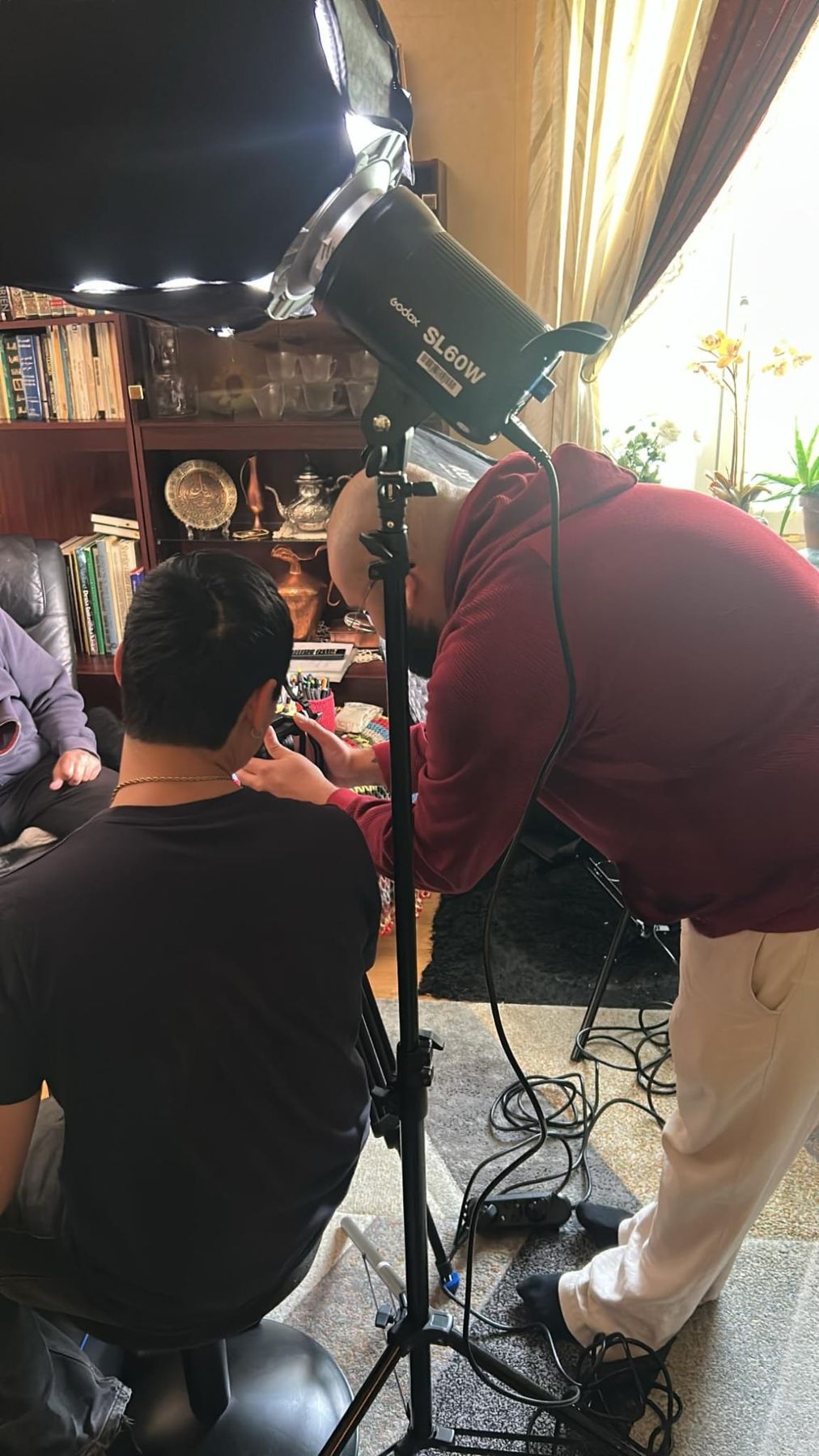 Two crew members checking the camera under a softbox