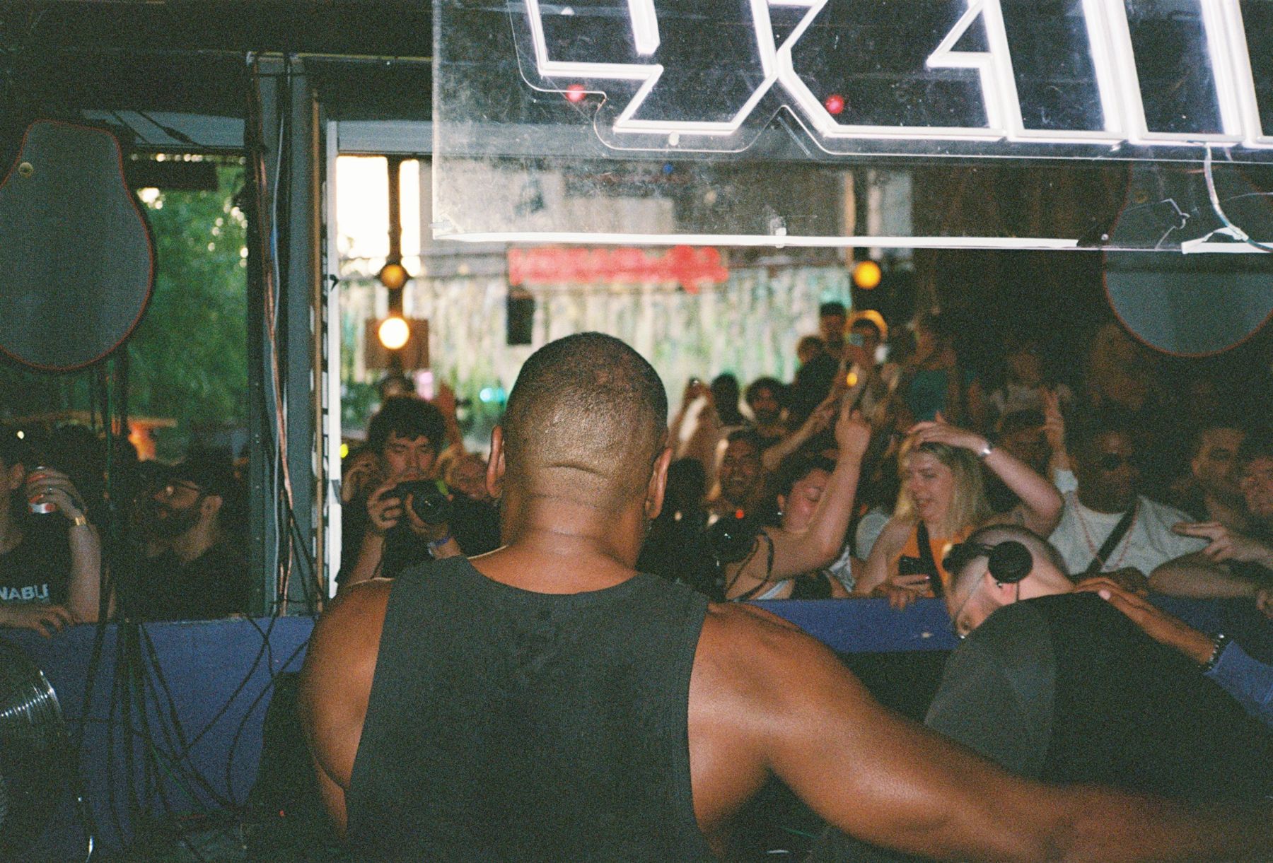 The original photo: a performer in a tank top seen from behind, facing a packed crowd