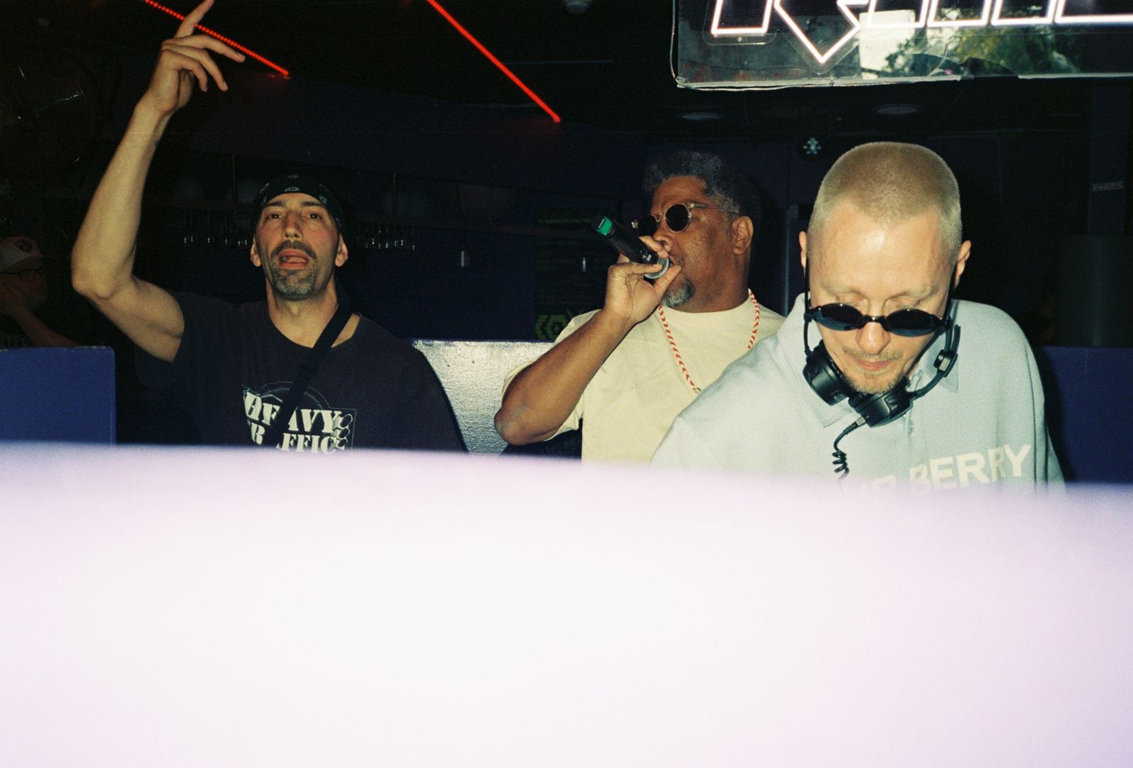 MC and DJs in the booth, one arm raised