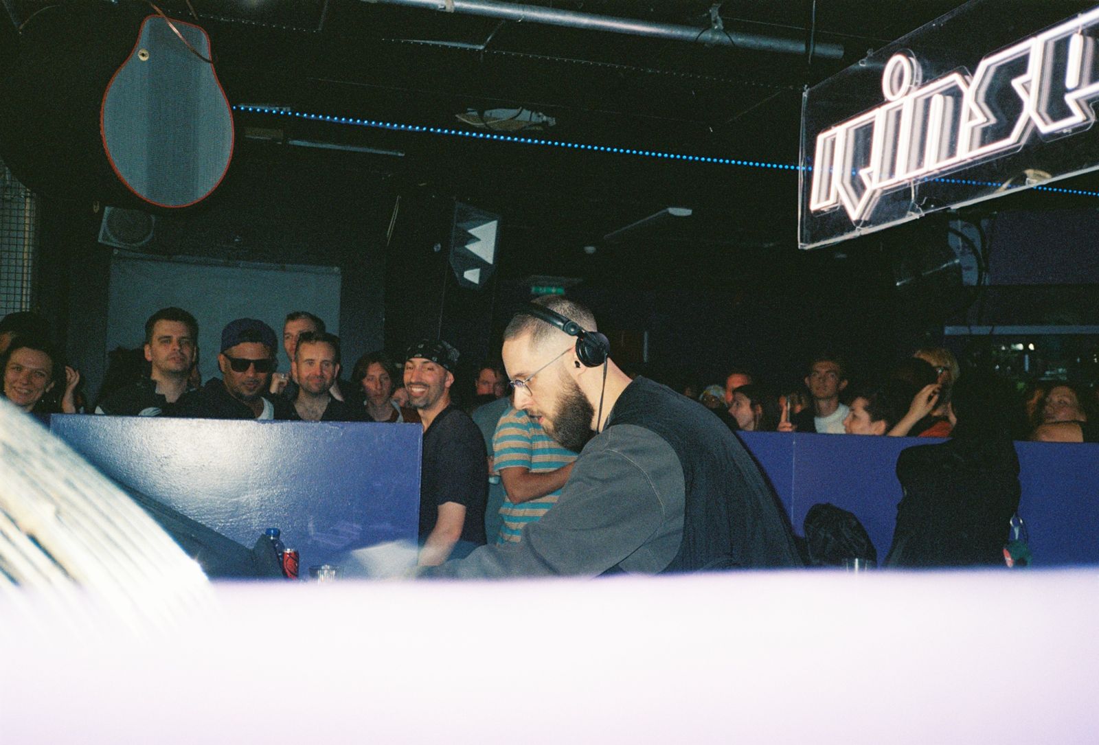 A DJ in headphones under the neon sign