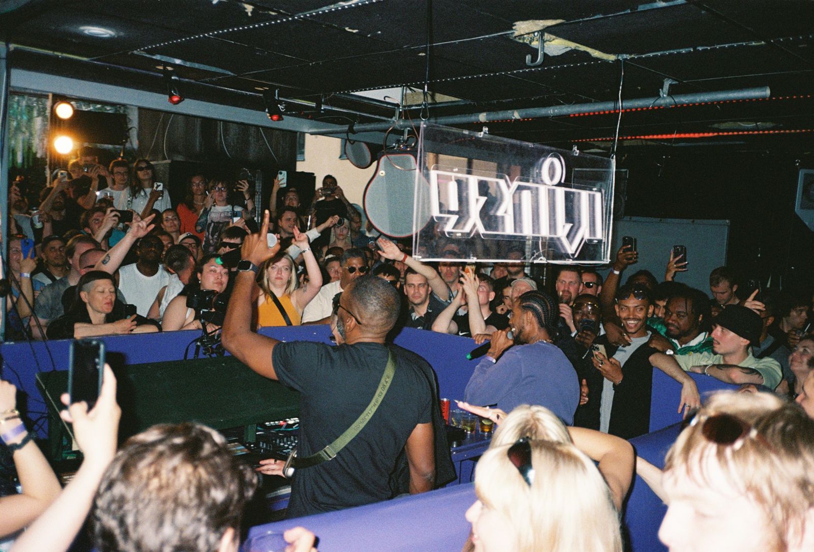 Performers in the booth facing a crowd filming on phones