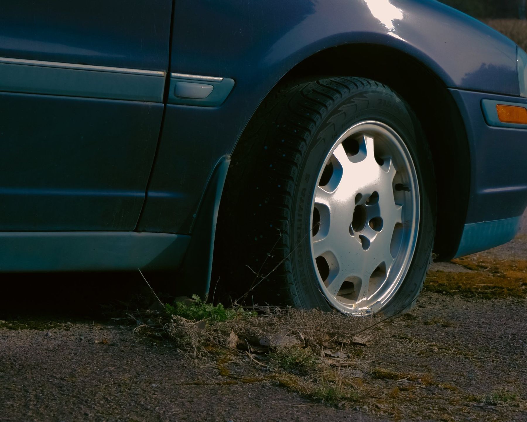 Close-up of a dark car wheel parked on grass